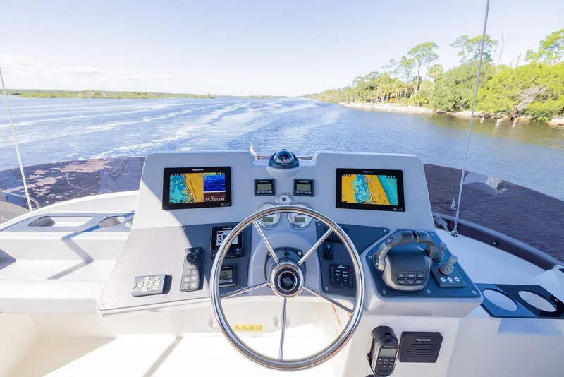 Slide: The Image of Helm of 2021 Beneteau Swift Trawler 41 with navigation screens, steering wheel, and river view. - 39