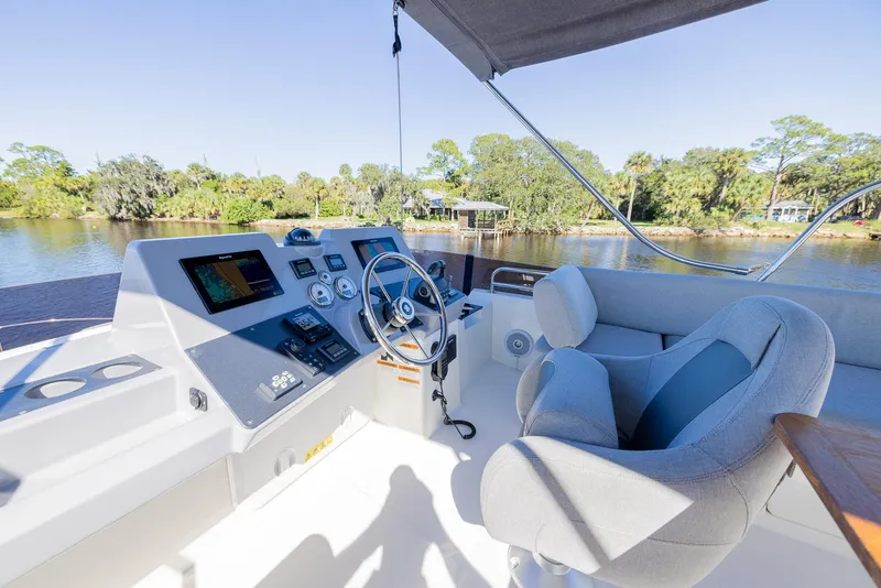 Slide: The Image of 2021 Beneteau Swift Trawler 41 helm station with scenic river view. - 40