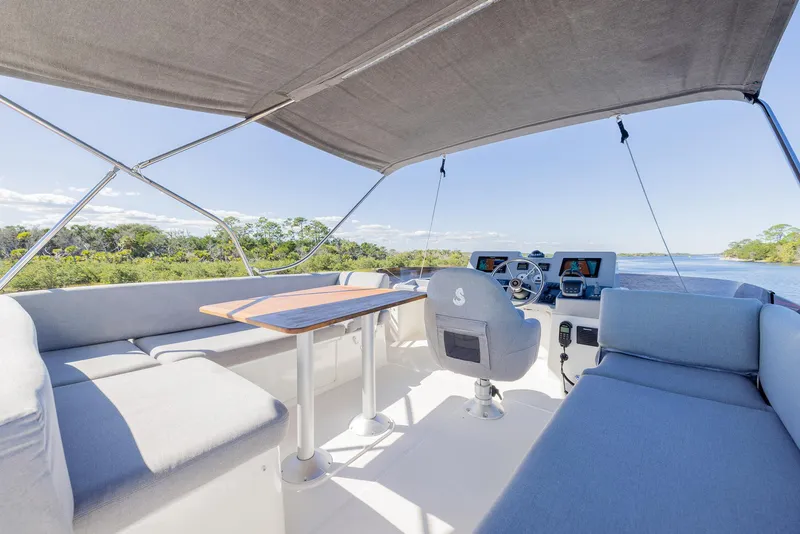 Slide: The Image of 2021 Beneteau Swift Trawler 41 interior with seating and helm, under canopy. - 42