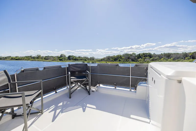 Slide: The Image of Beneteau Swift Trawler 41 deck, 2021 model, with chairs overlooking serene water and greenery. - 44