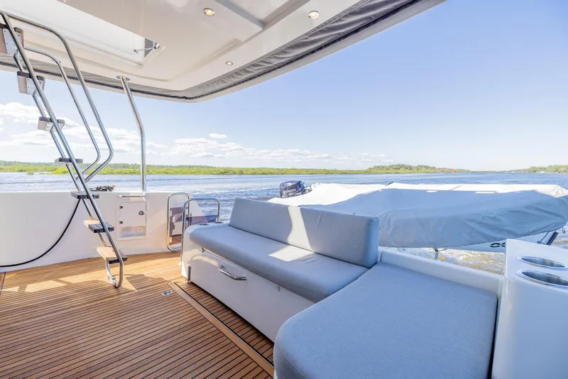 Slide: The Image of 2021 Beneteau Swift Trawler 41 deck with seating, overlooking serene water and lush landscape. - 47