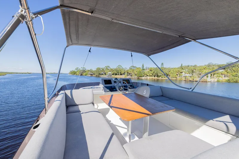 Slide: The Image of 2021 Beneteau Swift Trawler 41, spacious deck with seating, cruising on a scenic river. - 48
