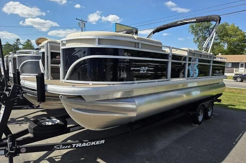 Slide: The Image of 2025 Sun Tracker SF 22 DLX pontoon boat on trailer, parked outdoors. - 2