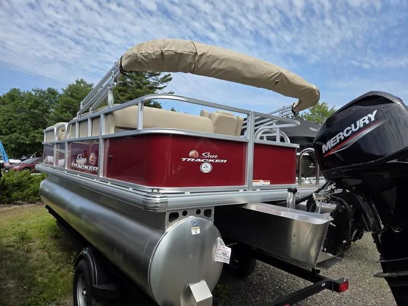 Slide: The Image of 2025 Sun Tracker PB 18 DLX pontoon boat with Mercury engine, parked outdoors. - 11