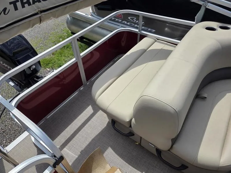 Slide: The Image of 2025 Sun Tracker PB 18 DLX pontoon boat with beige seating and red side panel. - 12