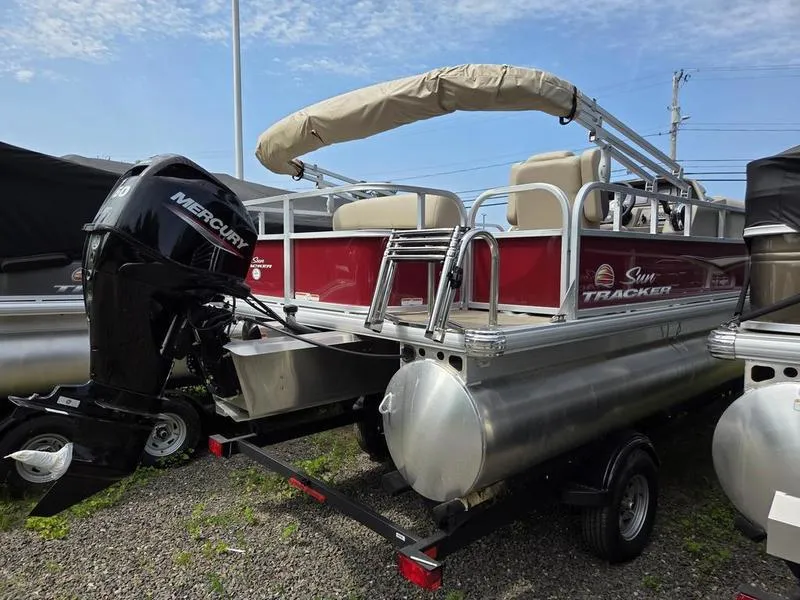 Slide: The Image of 2025 Sun Tracker PB 18 DLX pontoon boat with Mercury outboard motor, parked on trailer. - 4