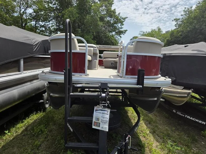 Slide: The Image of 2025 Sun Tracker PB 18 DLX pontoon boat on trailer, surrounded by trees. - 5