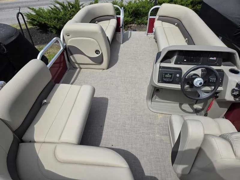 Slide: The Image of 2025 Sun Tracker PB 18 DLX pontoon boat interior with beige seating and steering console. - 7