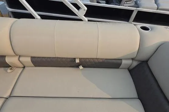 Slide: The Image of 2025 Sun Tracker FB 22 DLX boat interior with beige cushioned seating and cup holder. - 17