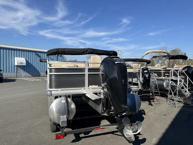 Slide: The Image of 2025 Sun Tracker FB 20 DLX pontoon boat with outboard motor in a parking lot. - 3