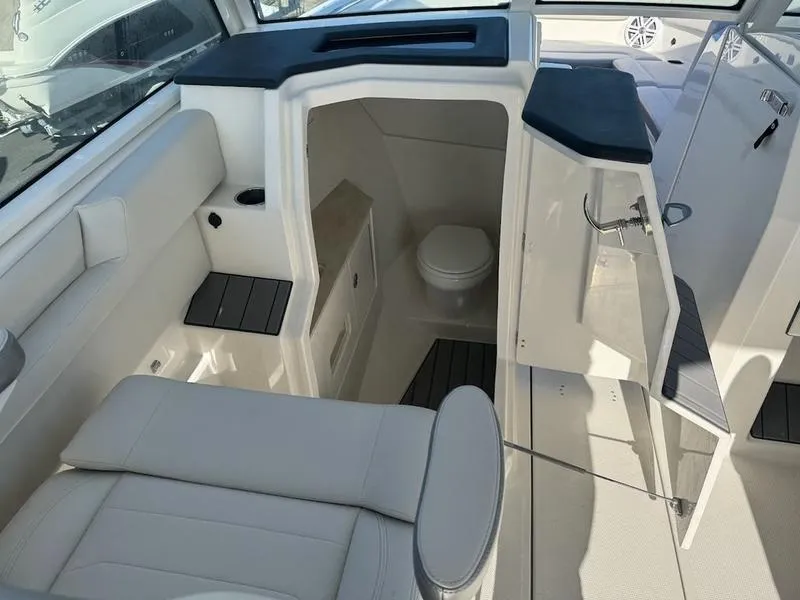 Slide: The Image of 2025 Sailfish 316 DC boat interior with seating and compact restroom. - 13