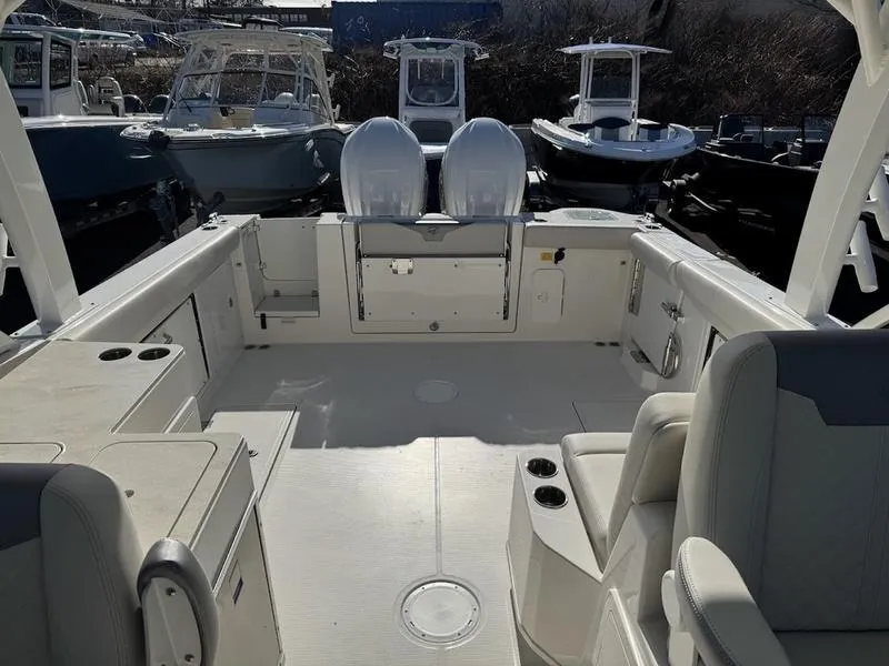 Slide: The Image of 2025 Sailfish 316 DC boat interior with seating and storage, docked among other boats. - 7