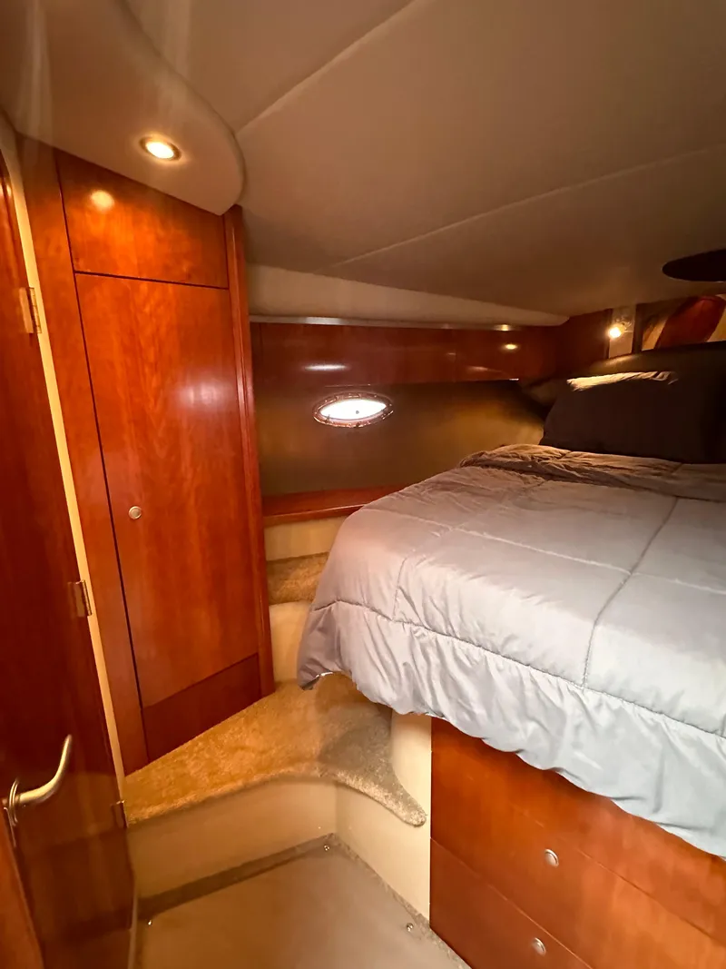 Slide: The Image of 2006 Cruisers Yachts 420 Express cabin with bed, wooden cabinetry, and soft lighting. - 35