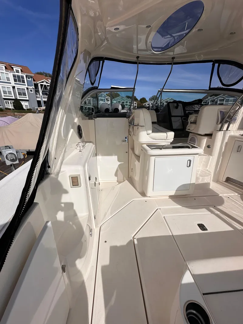 Slide: The Image of 2006 Cruisers Yachts 420 Express interior with seating and helm, docked near waterfront homes. - 4