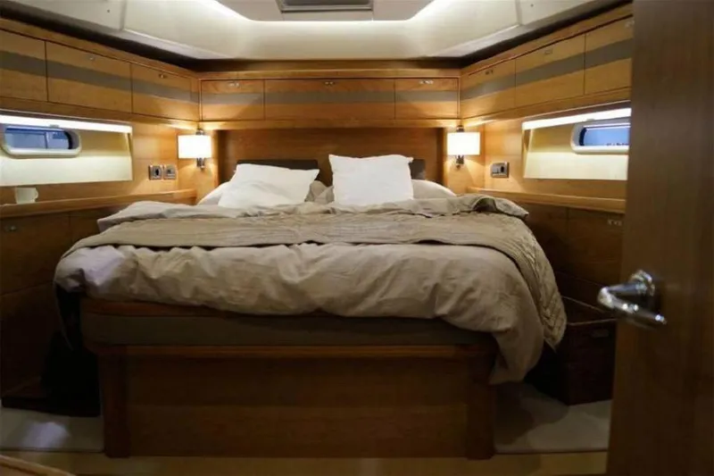 Slide: The Image of Luxurious bedroom interior of 2025 Moody 54 DS yacht with wooden finish and cozy bedding. - 25