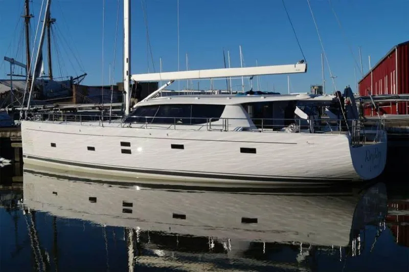 Slide: The Image of 2025 Moody 54 DS yacht docked, reflecting on calm water under clear blue sky. - 9