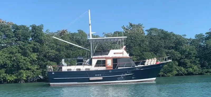 The Image of 1983 DeFever 41 yacht cruising on calm waters near lush greenery. - 0