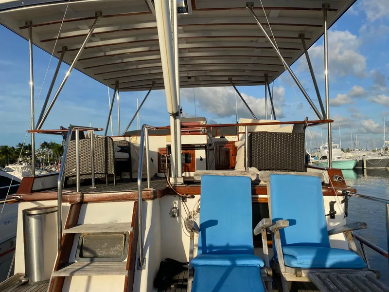 Slide: The Image of 1983 DeFever 41 yacht deck with blue chairs and canopy, docked at marina. - 10