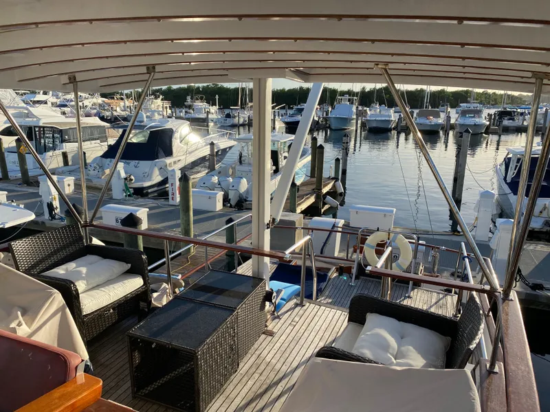 Slide: The Image of 1983 DeFever 41 yacht docked at marina with outdoor seating and view of boats. - 14
