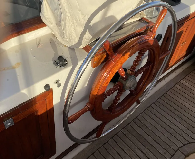 Slide: The Image of Wooden steering wheel on 1983 DeFever 41 boat, with polished metal rim and wooden deck. - 15
