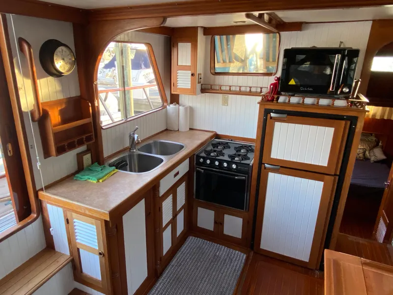 Slide: The Image of 1983 DeFever 41 yacht kitchen with wood cabinetry, dual sink, stove, and microwave. - 20