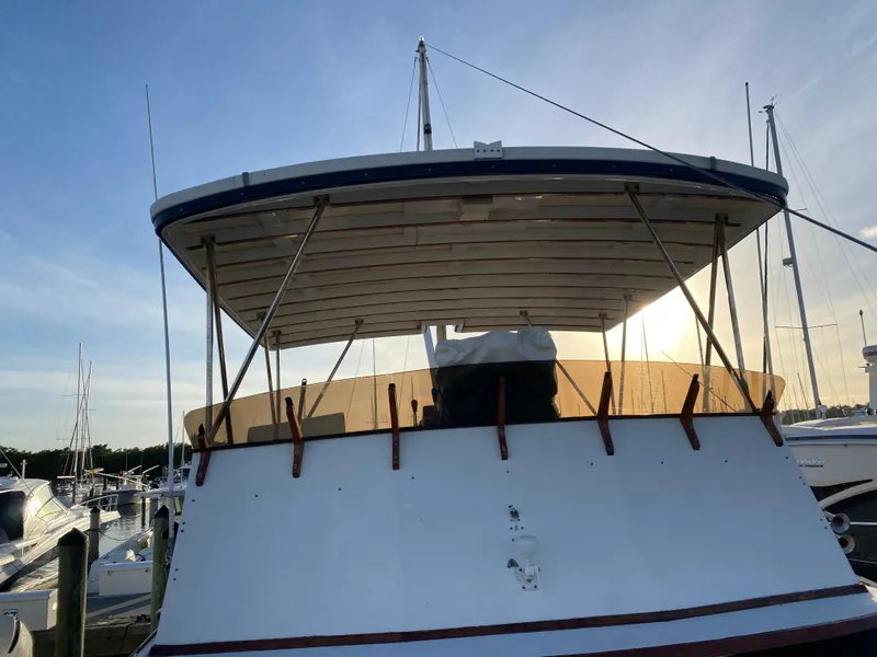 Slide: The Image of 1983 DeFever 41 yacht docked at marina, rear view with canopy and clear sky. - 8
