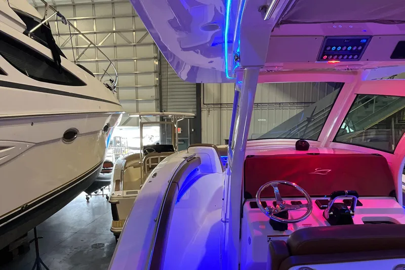 Slide: The Image of 2021 Scout 305 LXF boat interior with illuminated dashboard in a storage facility. - 18