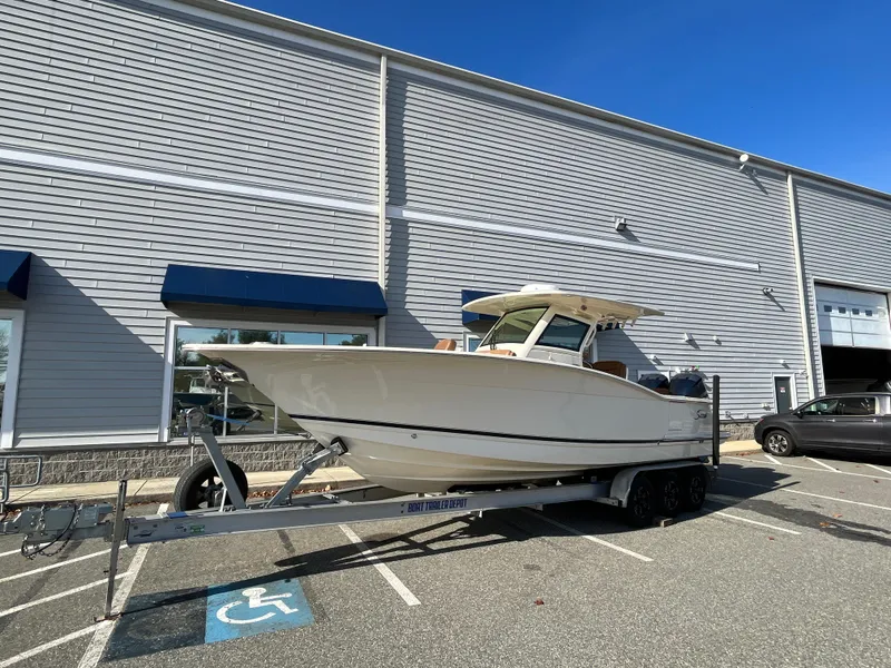 Slide: The Image of 2021 Scout 305 LXF boat on trailer in parking lot. - 2