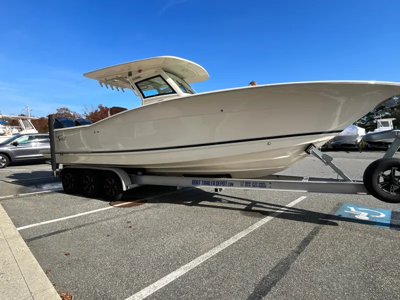 Slide: The Image of 2021 Scout 305 LXF boat on trailer in parking lot, clear blue sky. - 5