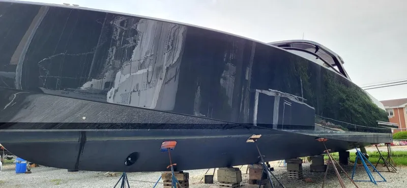 Slide: The Image of 2023 VanDutch 56 yacht on stands, surrounded by greenery and trailers. - 3