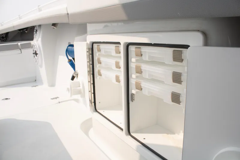 Slide: The Image of 2025 Yellowfin 32 Offshore boat storage compartment with organized tackle boxes. - 11