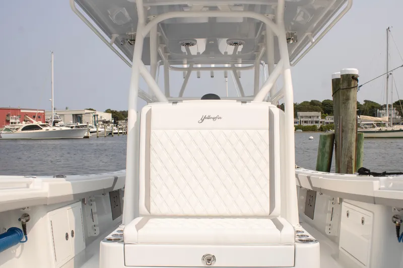 Slide: The Image of 2025 Yellowfin 32 Offshore boat interior with white seating, docked at a marina. - 12