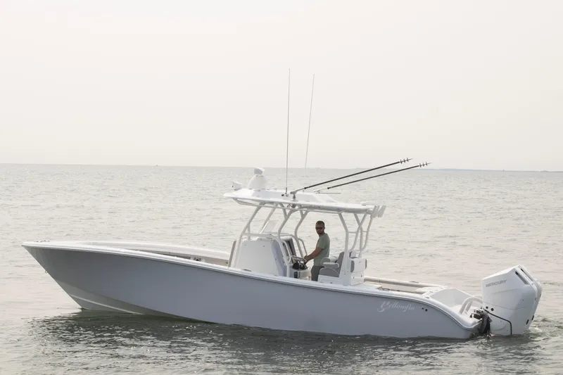 Slide: The Image of 2025 Yellowfin 32 Offshore boat on calm sea with a person at the helm. - 3