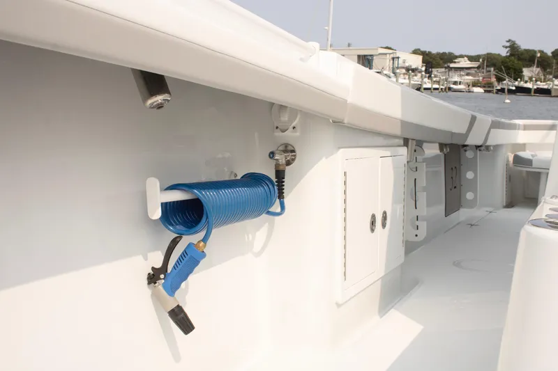 Slide: The Image of 2025 Yellowfin 32 Offshore boat deck with coiled blue hose and storage compartments. - 9