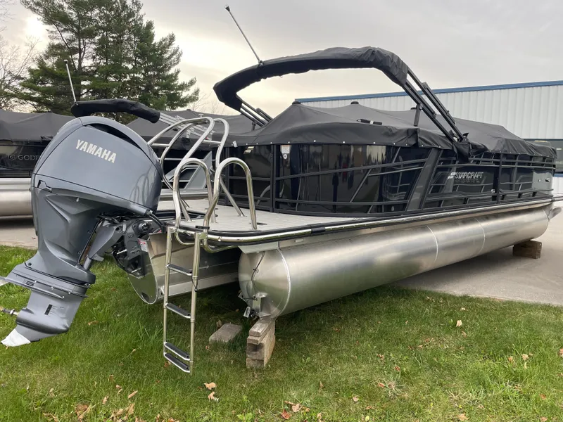 The Image of 2024 Starcraft SLS 5 pontoon boat with Yamaha outboard motor, parked on grass. - 1
