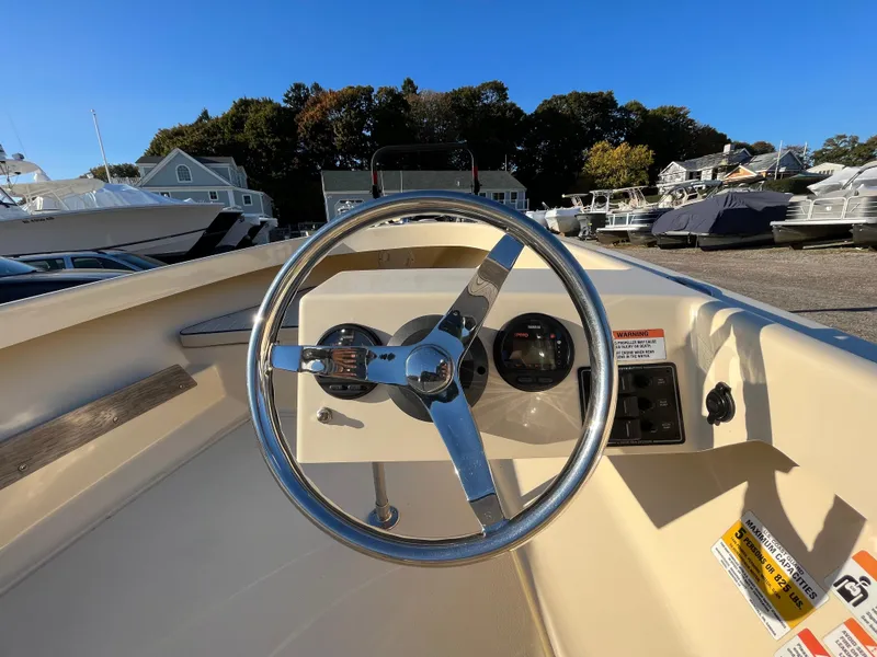 Slide: The Image of Steering wheel of a 2016 Rossiter Shoreline 14 boat in a marina setting. - 11