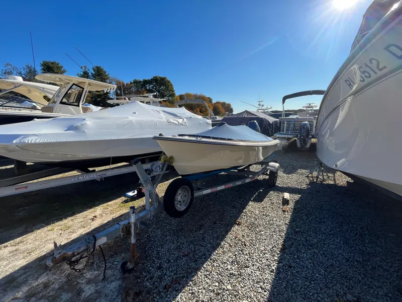 Slide: The Image of 2016 Rossiter Shoreline 14 boat on trailer, parked outdoors under clear blue sky. - 16