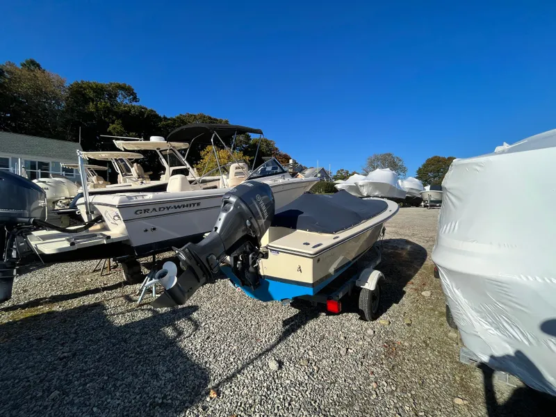 Slide: The Image of 2016 Rossiter Shoreline 14 boat on trailer, parked outdoors under clear blue sky. - 18