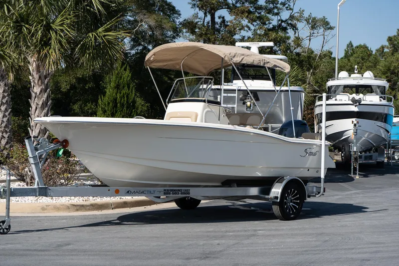 Slide: The Image of 2025 Scout 195 Sportfish boat on trailer, parked outdoors. - 2