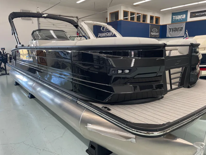 Slide: The Image of 2025 Starcraft RX 25 Q DC pontoon boat in showroom, sleek black design. - 22