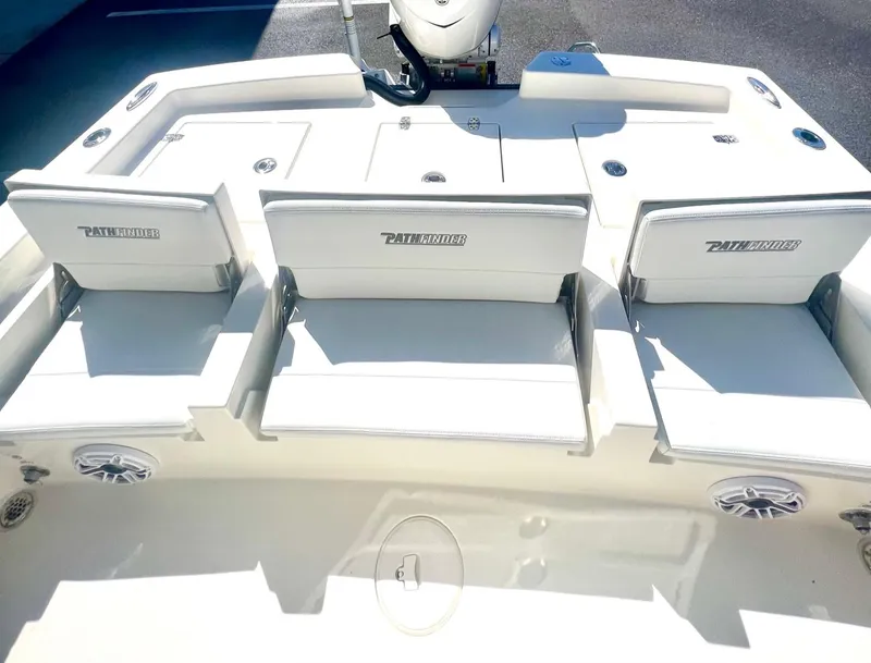 Slide: The Image of 2025 Pathfinder 2600 TRS boat seating area with white cushioned seats and storage compartments. - 2