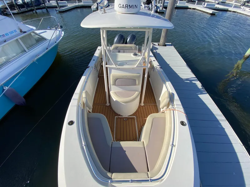 Slide: The Image of 2018 Cobia 237 CC boat docked, featuring spacious seating and Garmin equipment. - 10