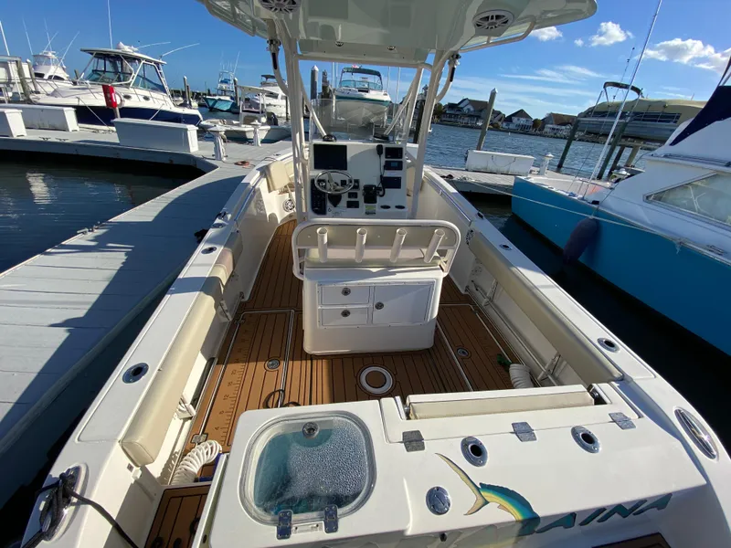 Slide: The Image of 2018 Cobia 237 CC boat docked, featuring spacious deck and modern console. - 11