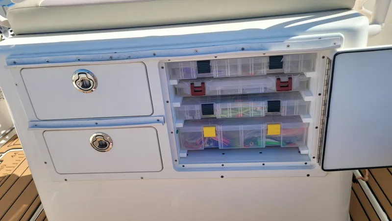Slide: The Image of 2018 Cobia 237 CC boat storage with organized tackle boxes and drawers. - 14