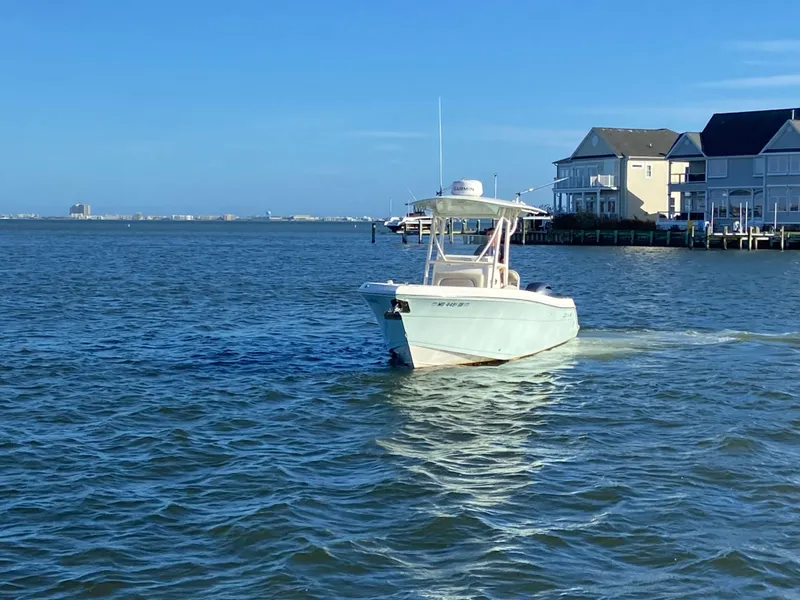 Slide: The Image of 2018 Cobia 237 CC boat cruising near waterfront homes. - 3