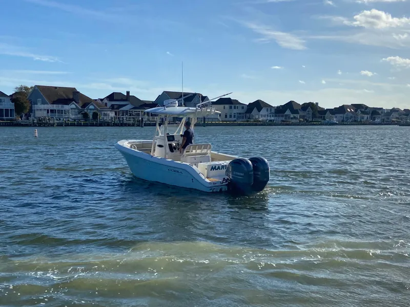 Slide: The Image of 2018 Cobia 237 CC boat on water near residential shoreline. - 7