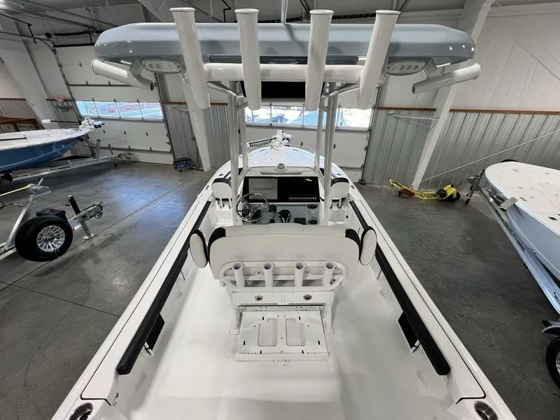 Slide: The Image of 2025 Tidewater 2300 Carolina Bay boat interior in showroom, featuring rod holders and console. - 34