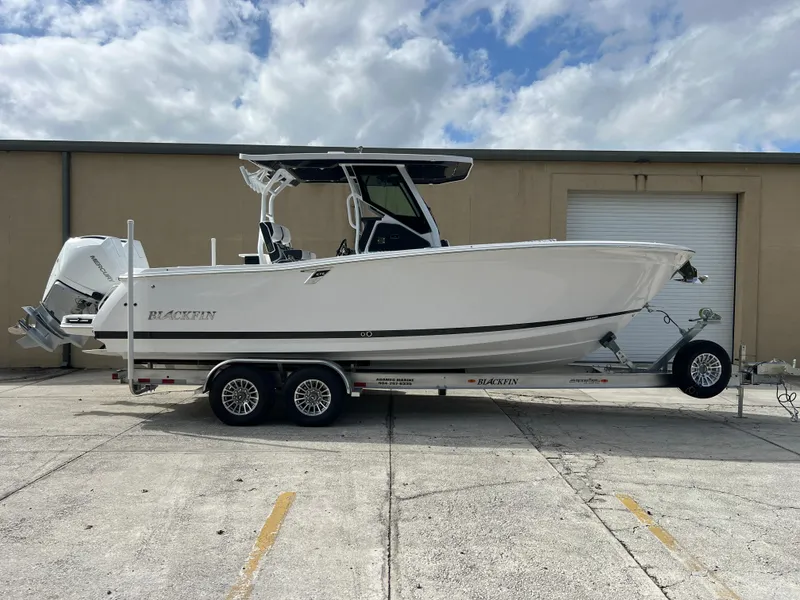 Slide: The Image of 2025 Blackfin 272 CC boat on trailer, parked outdoors under cloudy sky. - 17