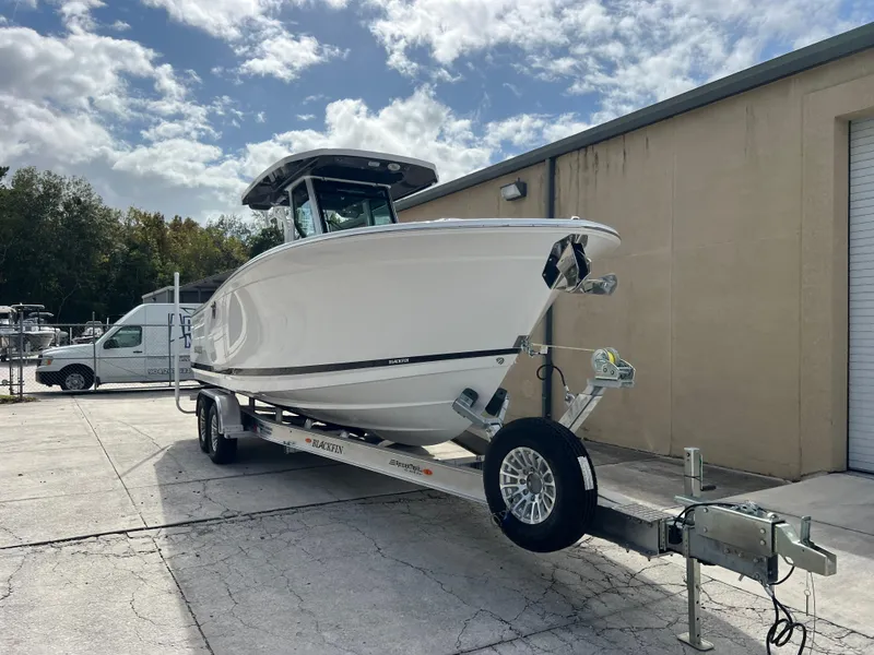 Slide: The Image of 2025 Blackfin 272 CC boat on trailer, parked outdoors under cloudy sky. - 19