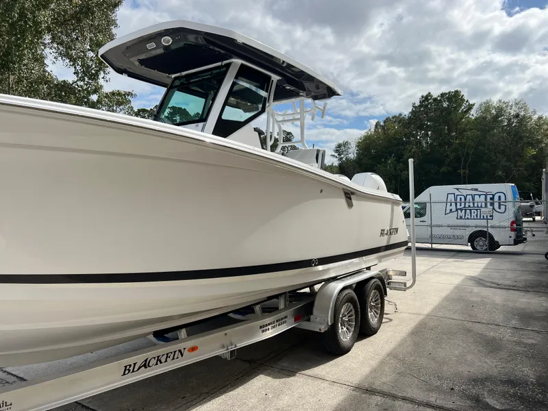 Slide: The Image of 2025 Blackfin 272 CC boat on trailer, parked outdoors under cloudy sky. - 23